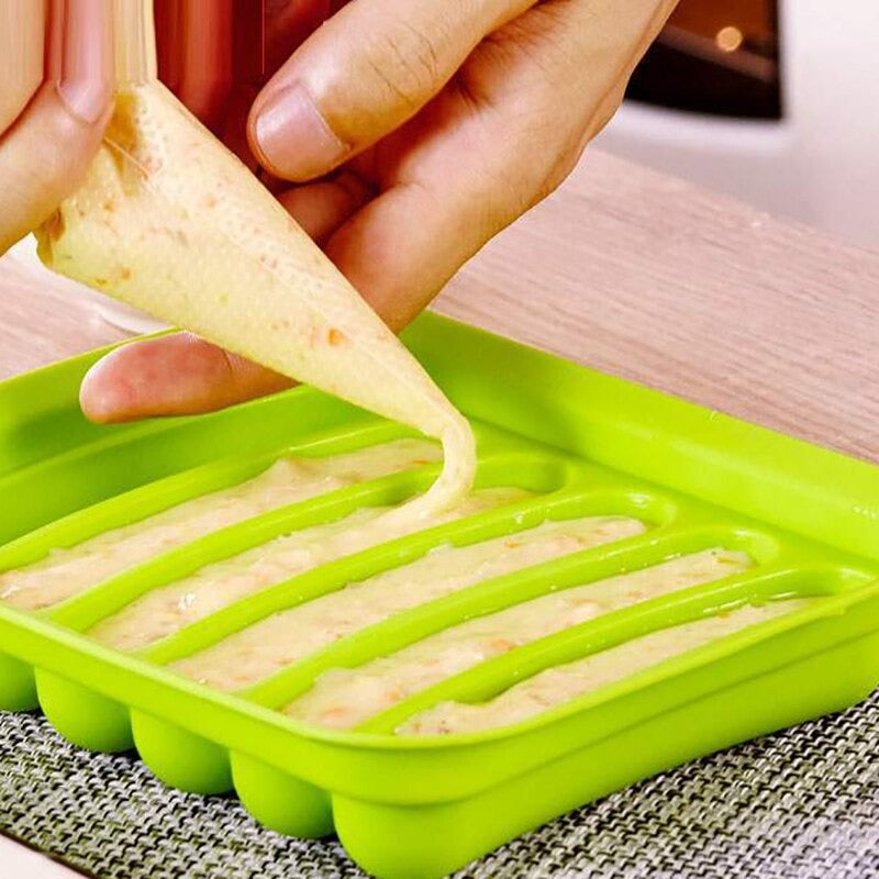 A green sausage mold with a pair of hands filling the mold with sausage filling.