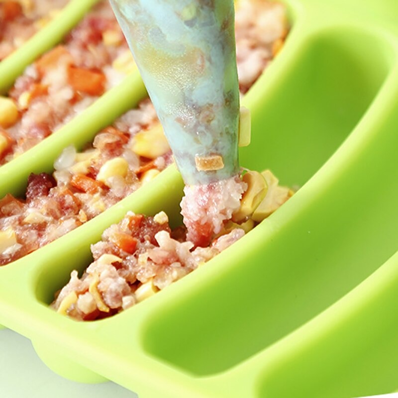 A close up of a green sausage mold maker with sausage fillings being placed into the molds.