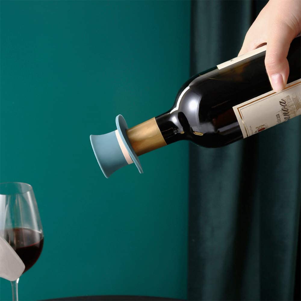 A blue colored silicone wine stopper shaped as a top hat on top of a bottle of wine. A hand is turning the bottle upside down to show how no liquid is leaking when the stopper is used.