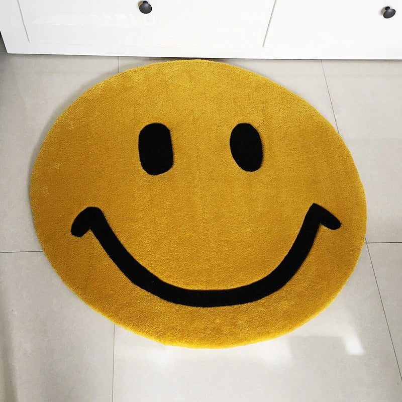 A mat in a bathroom which is designed to look like a smiley face emoji.