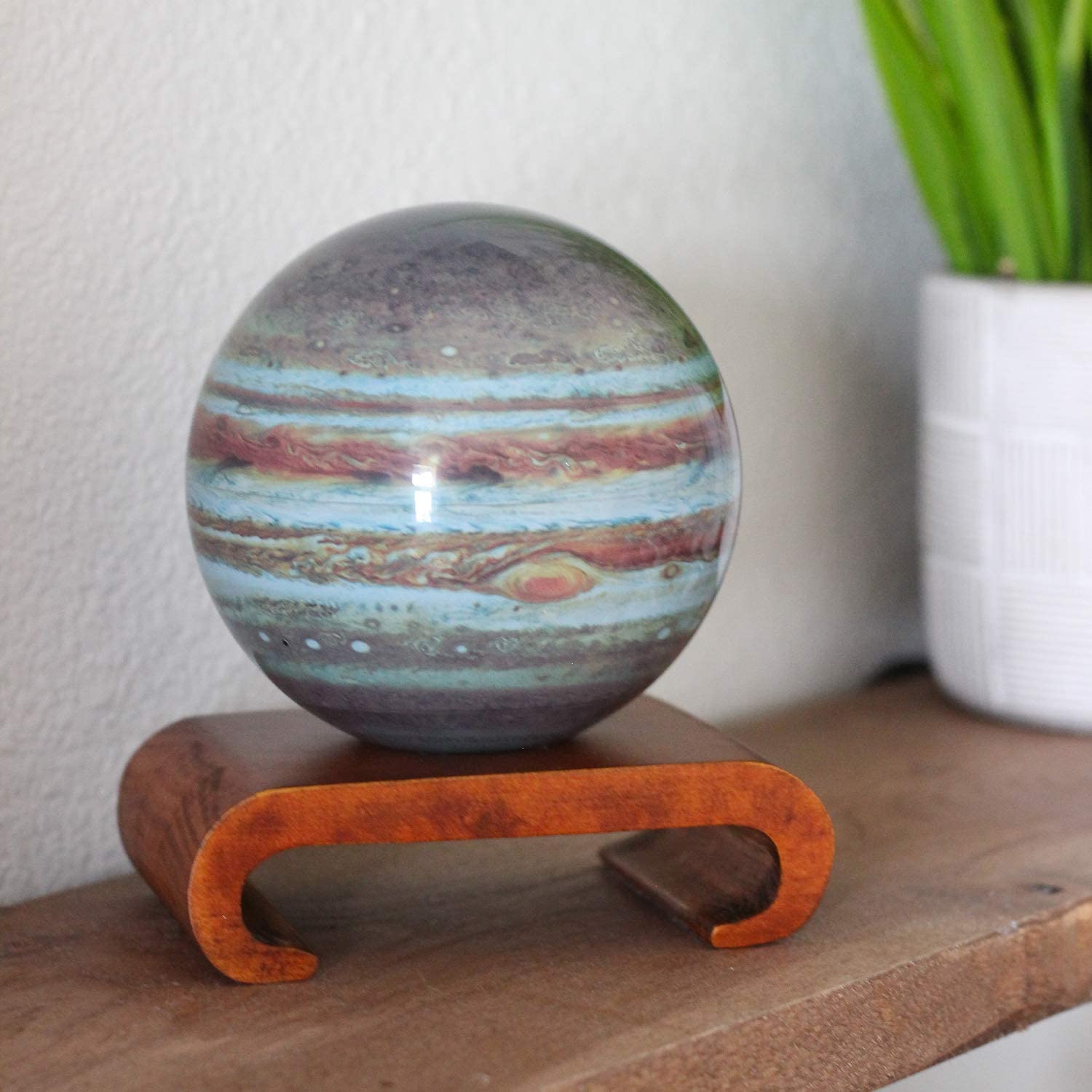 A spinning version of planet Jupiter on a wooden stand.
