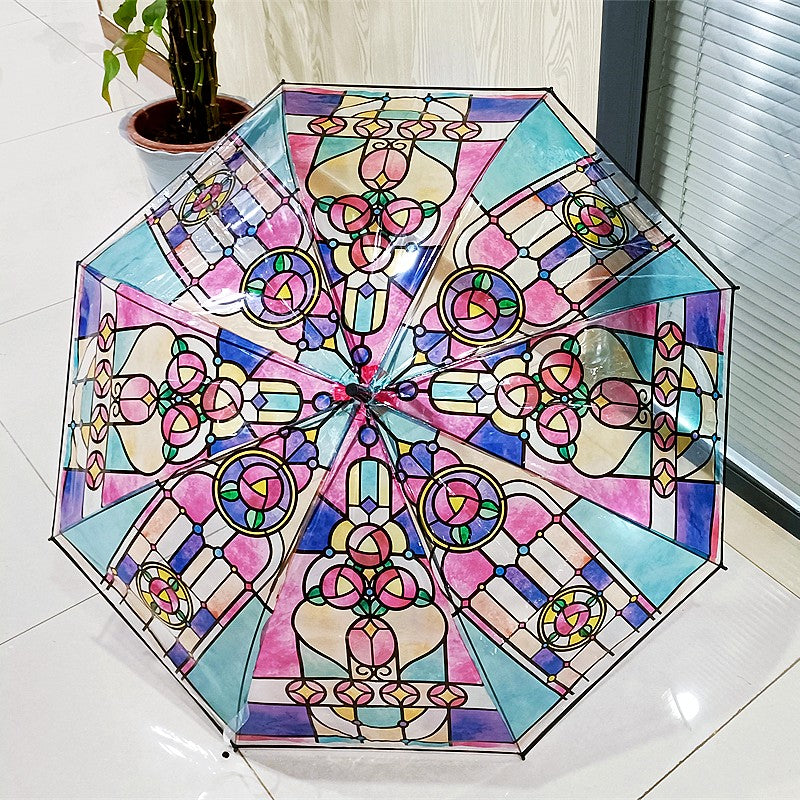 A colorful umbrella with a stained glass pattern on it resting on a tiled floor.