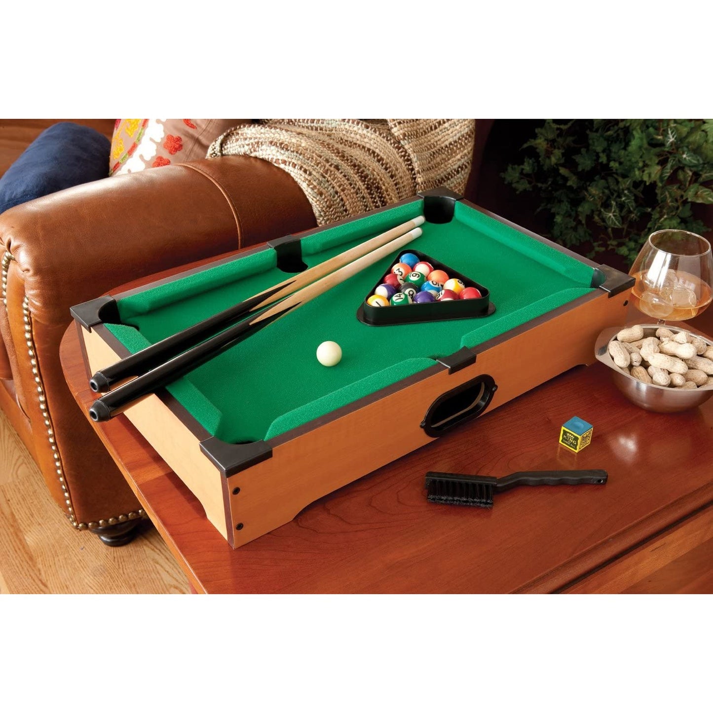 A miniature table-top pool game set sitting on a small side table.