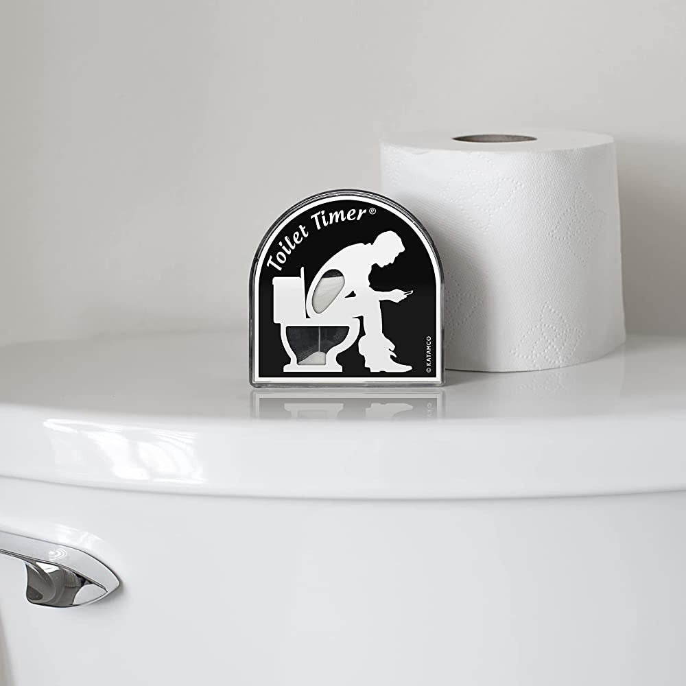 A Toilet Timer device is sitting on the back of a toilet cover next to a roll of toilet paper.