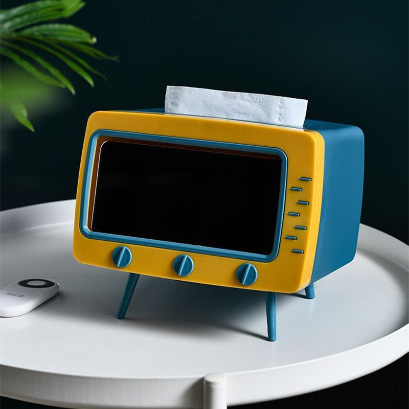 AA yellow and blue TV shaped tissue box sitting on a white table with a tissue sticking out the top of it