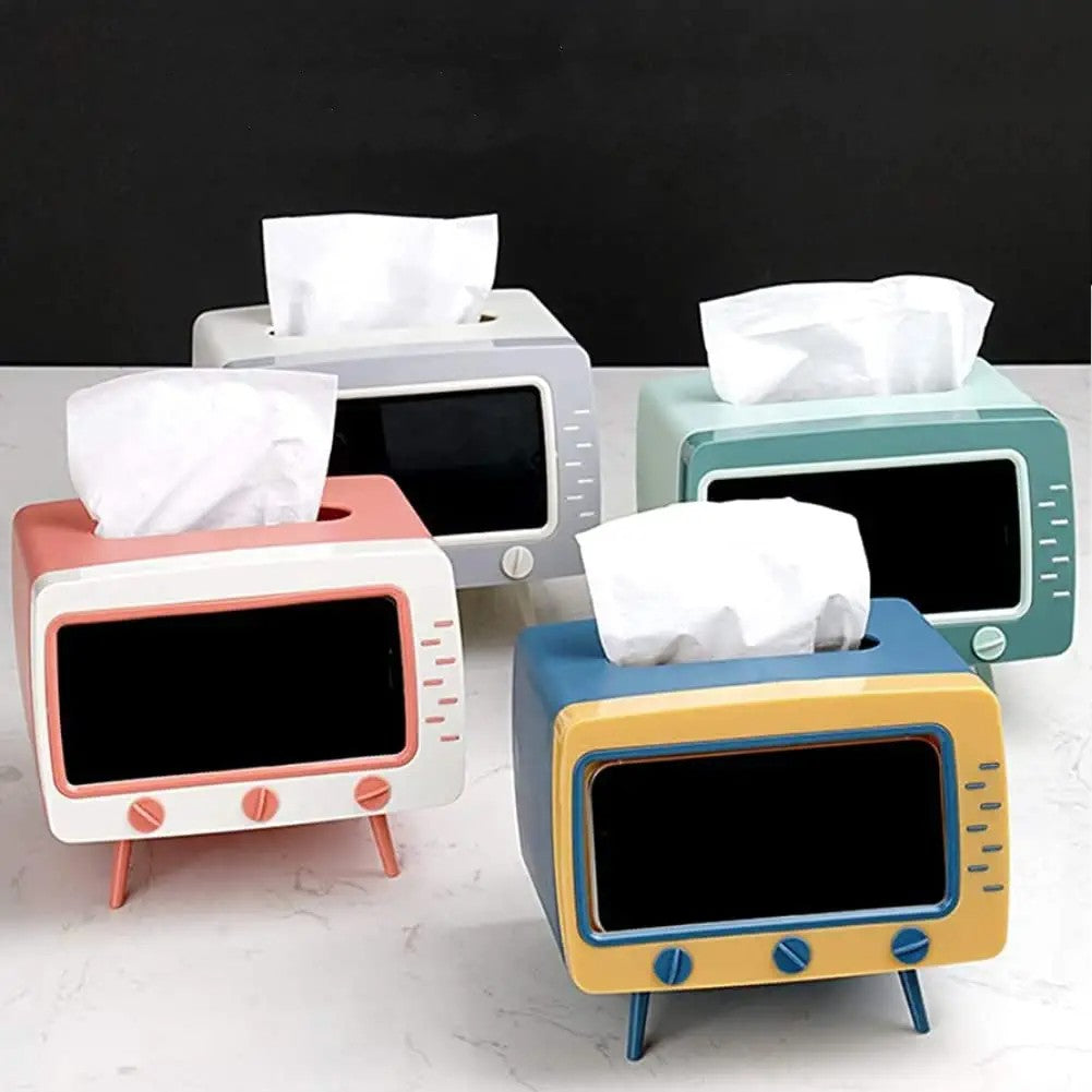 Four tissue boxes shaped like television sets. They all have tissues coming out of the top. These tissue boxes also double as a mobile phone holder.