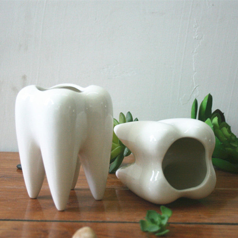 Two empty teeth shaped planter pots with one tipped on its side.