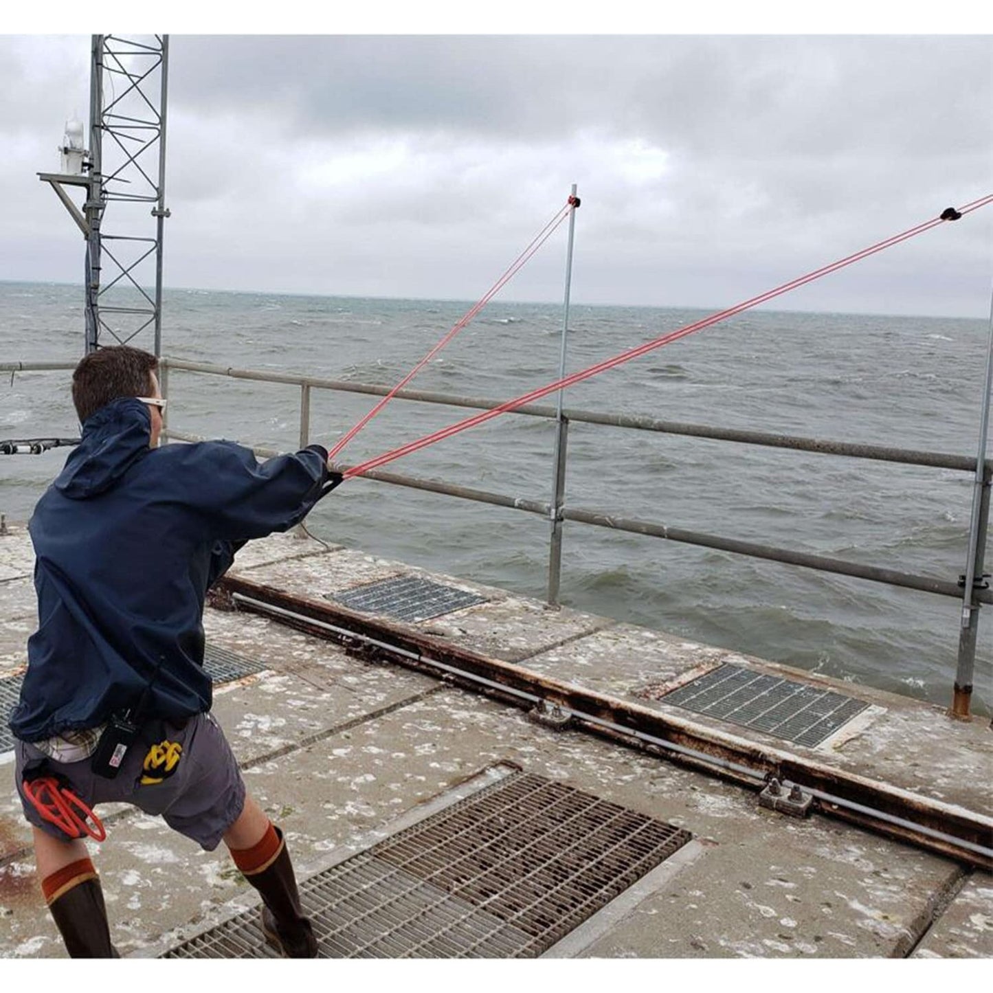 A person is on a ship about to use a water balloon launcher to launch an item into the ocean.