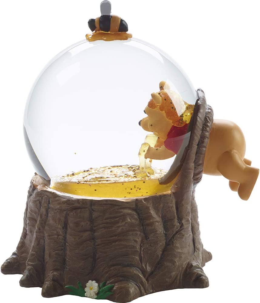 A side view of a Winnie the Pooh snow globe. It shows Winnie dipping his hands into a giant hive of honey. 