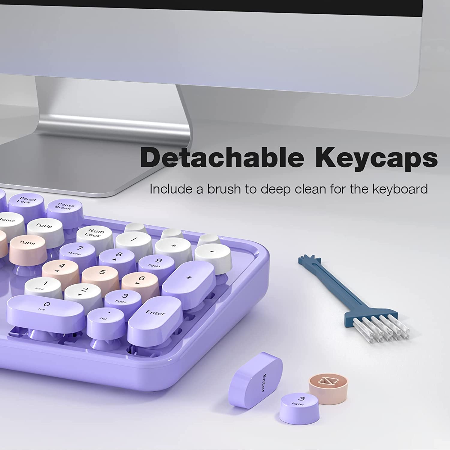 A close up of a purple and white colored wireless keyboard with some of the keycaps removed plus a small brush. The headline reads, 'Detachable keycaps. Includes a brush to deep clean the keyboard.'