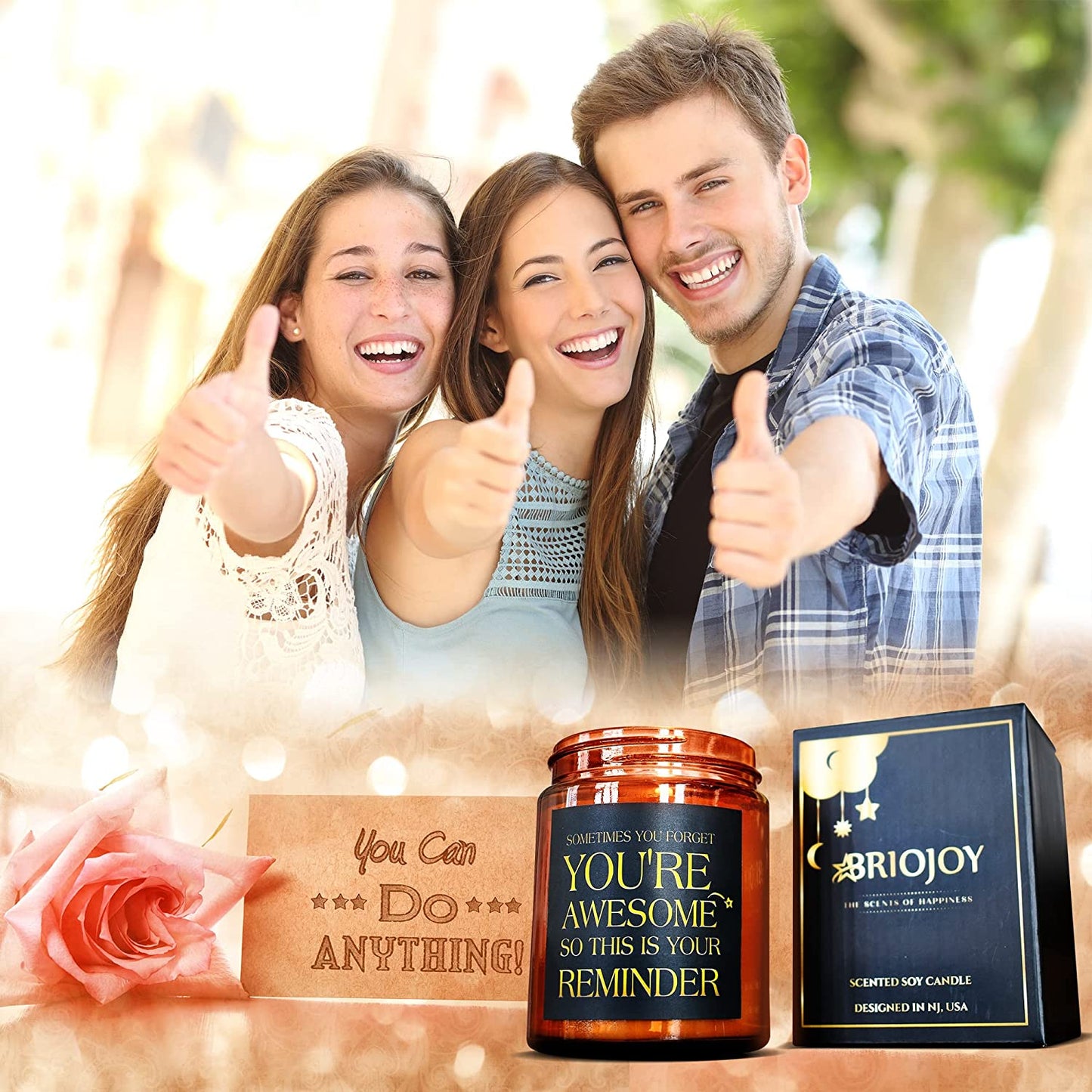 Two women and a guy are giving their thumbs up to the camera. There is also a candle which has a quote printed on it which says, "Sometimes You Forget You’re Awesome So This Is Your Reminder.”