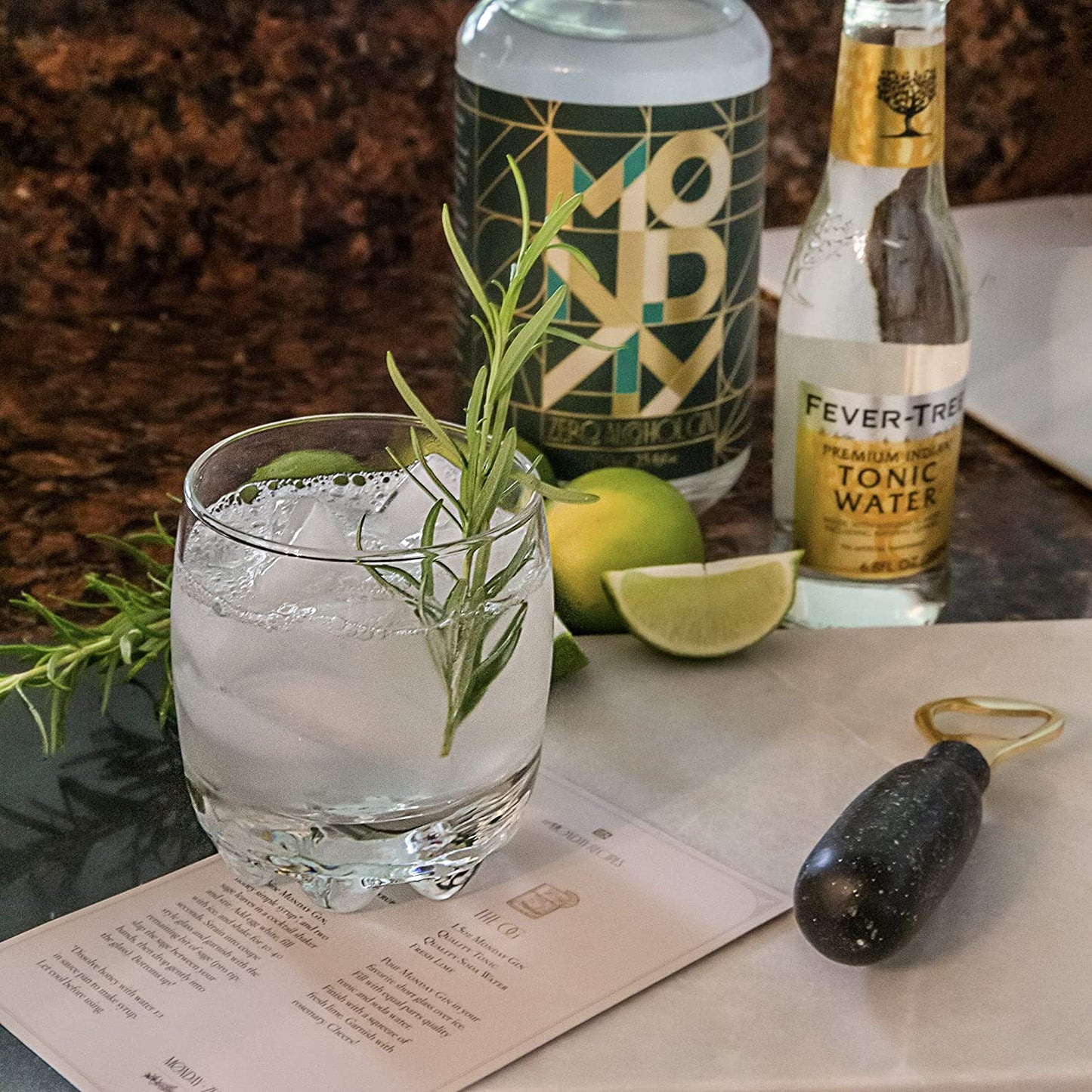 A refreshing looking cocktail with ice. There is a bottle of non-alcoholic Monday gin in the background along with a bottle of tonic water.
